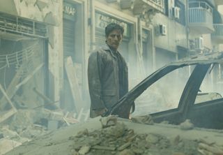 Sergio (Joaquín Furriel) de pie entre las ruinas en la película que en paz descanse (2024).