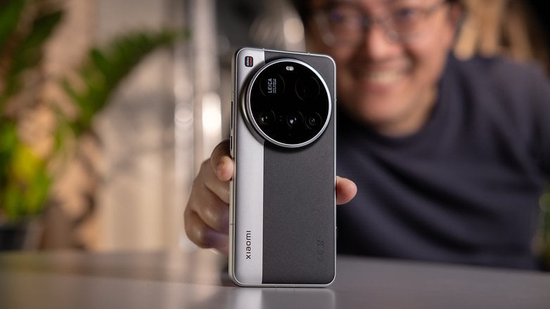 Xiaomi 15 Una persona con un teléfono ultra inteligente, sonriendo en la parte posterior del área verde.