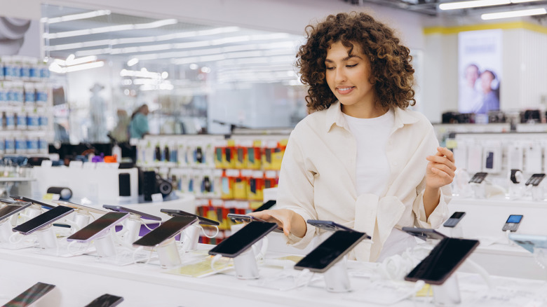 Una persona navegando por un teléfono inteligente a la venta en una tienda de electrónica