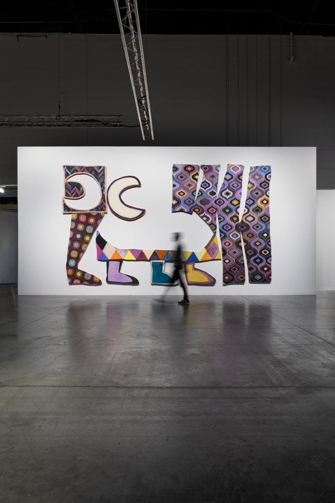 Imagen de una persona parada frente a la pintura a gran escala de Justine Hill en Art Basel Miami Beach