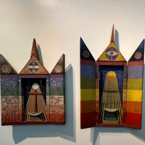 Dos coloridas obras de arte de madera con símbolos de contraventanas y ojos cuelgan de la pared de un museo